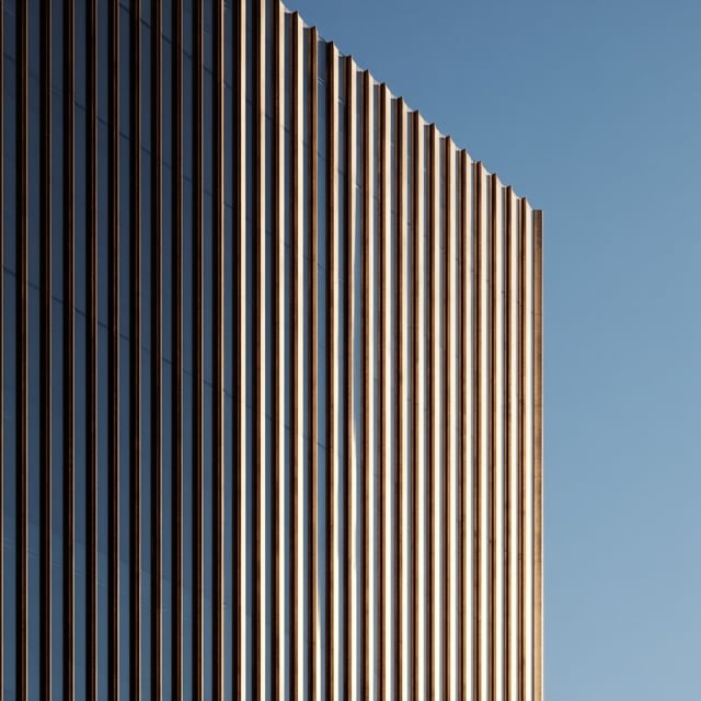 Close-up of an office tower's vertical façade fins against a blue sky