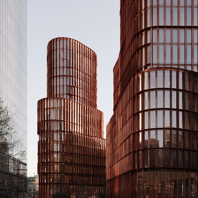 Two curved office towers clad in copper-coloured fins in Stockholm